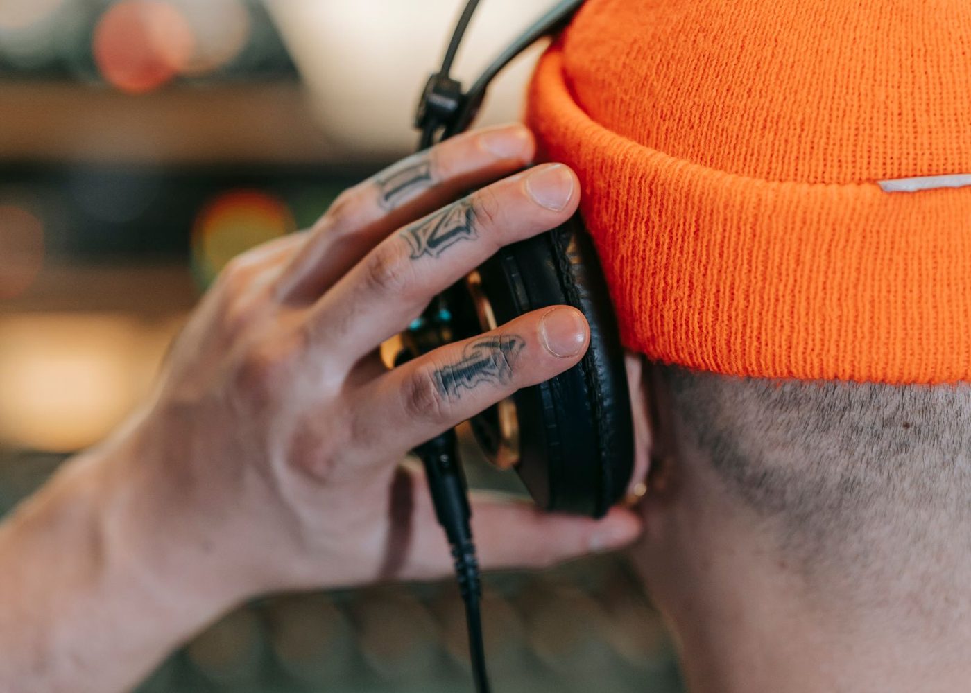 A DJ wearing over-ear headphones with a hand resting on the ear cup